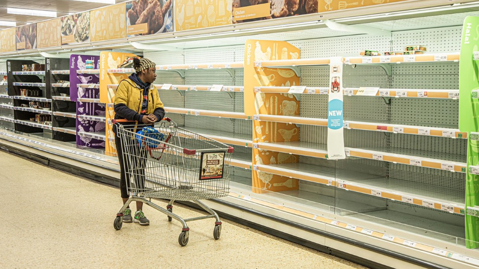 A shopper scanning empty supermarket shelves in London during the coronavirus pandemic.