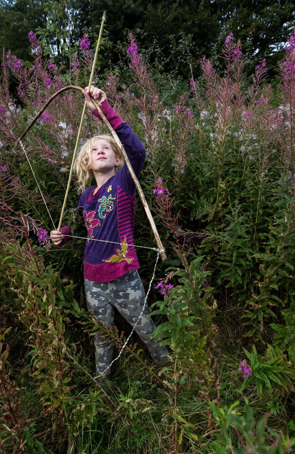 Portrait of Jessica holding a bow and arrow in a meadow