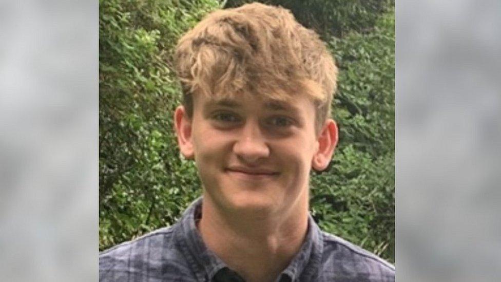 A young man with brown hair smiling at the camera