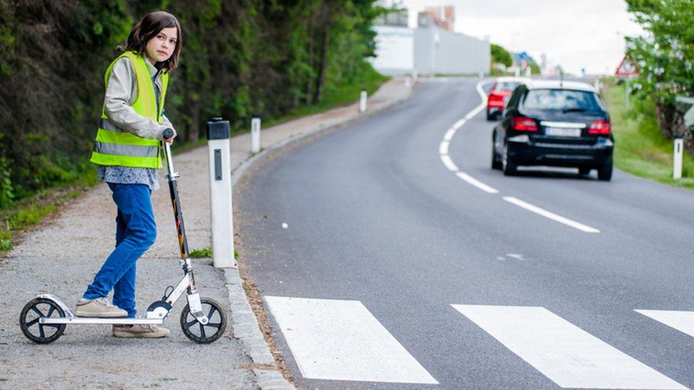 boy-getting-ready-to-cross-the-road-on-a-scooter