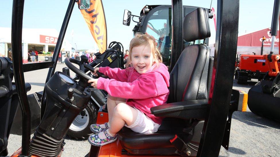 A girl sits in the cab of a digger at Balmoral Show