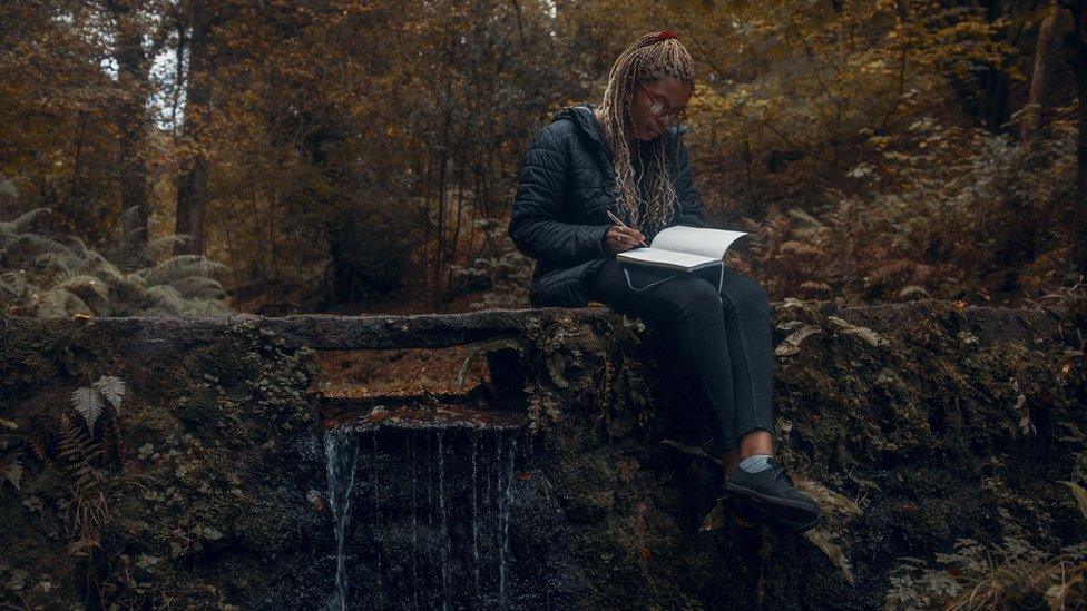 A woman writing in the forest