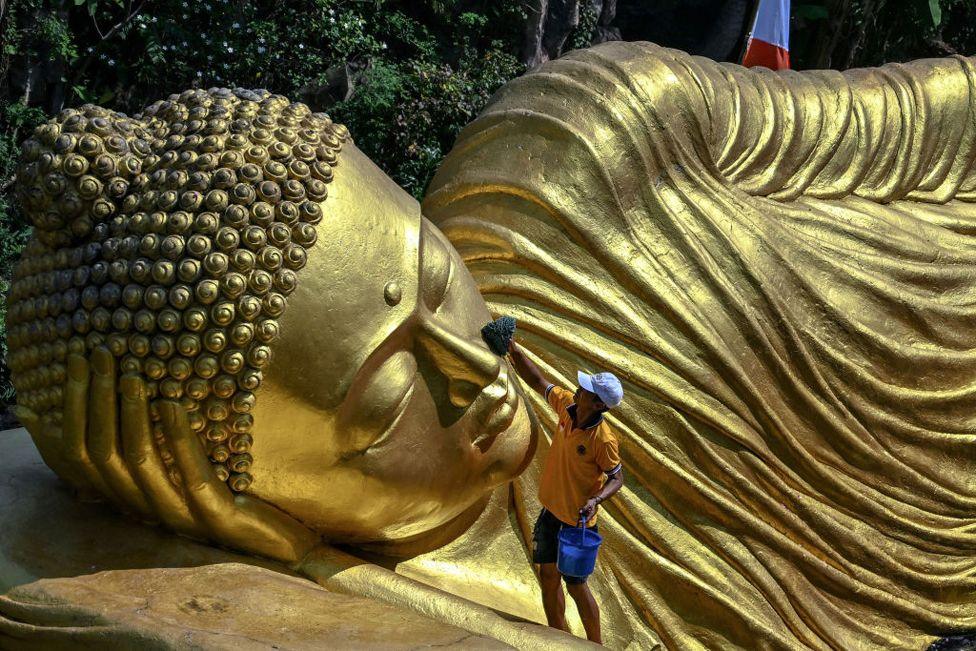 A worker cleans a Buddha statue at the Maha Vihara Mojopahit temple in Mojokerto on 15 May 2024