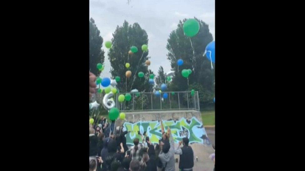 People releasing blue and green balloons