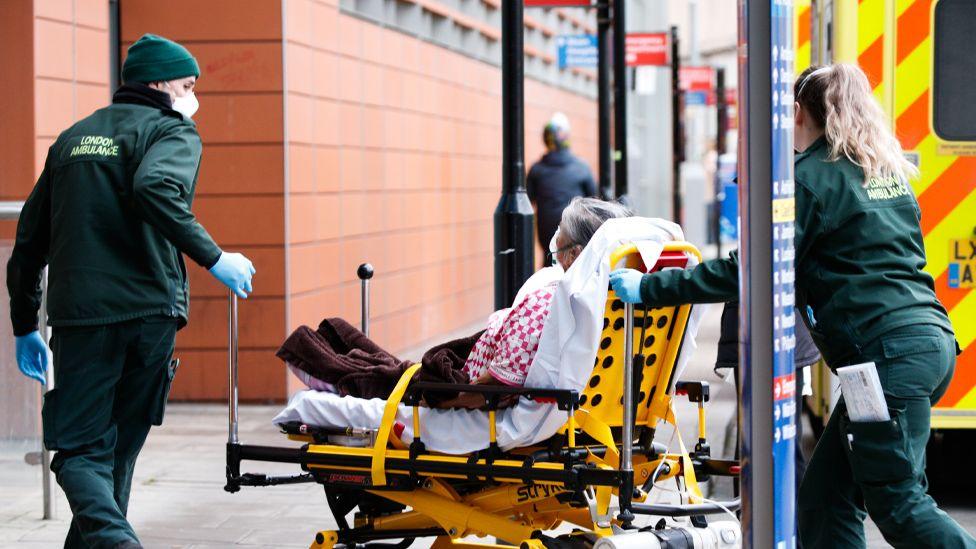 A patient is wheeled off an ambulance by paramedics