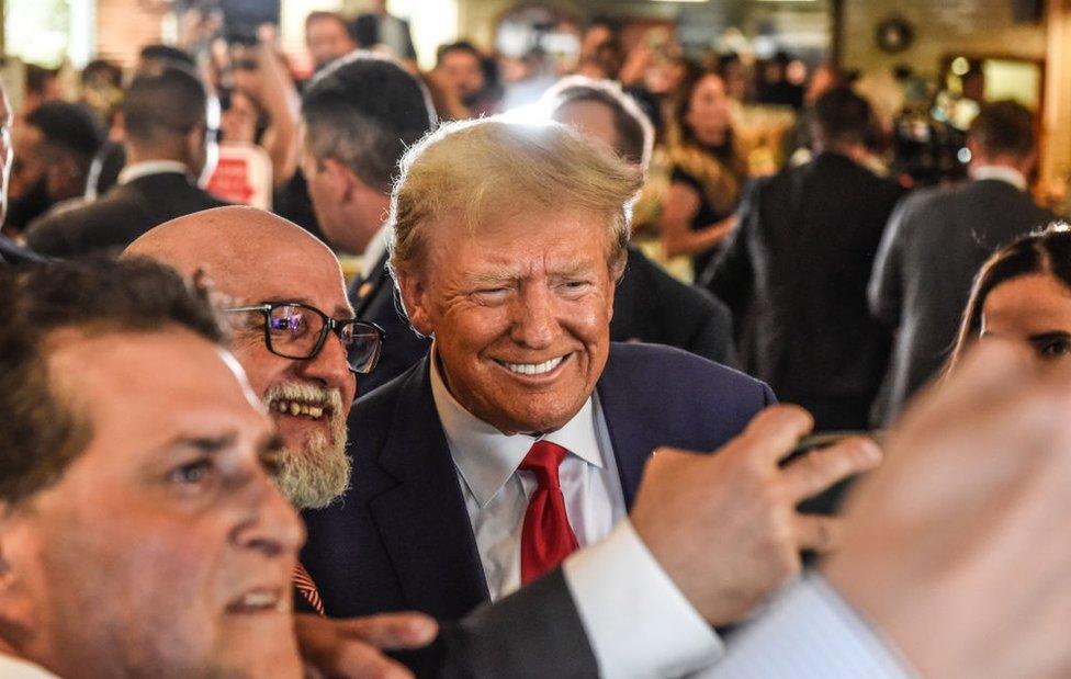 Donald Trump poses with patrons during a surprise visit to the Versailles restaurant in Little Havana, Miami, after pleading not guilty in court