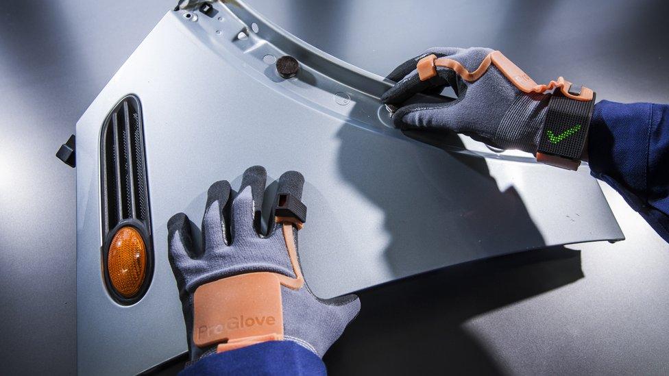 Worker attaching a nut to a car panel