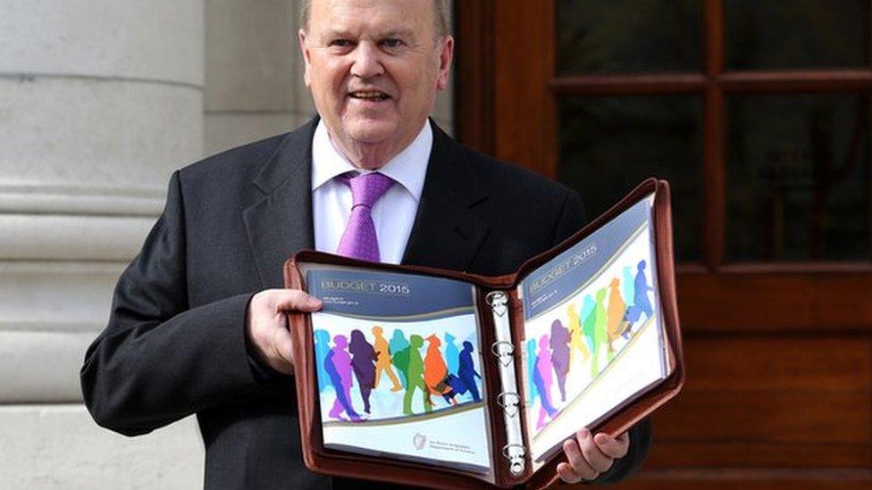 Irish Finance Minister Michael Noonan poses for pictures with the Irish 2015 budget outside the government buildings in Dublin