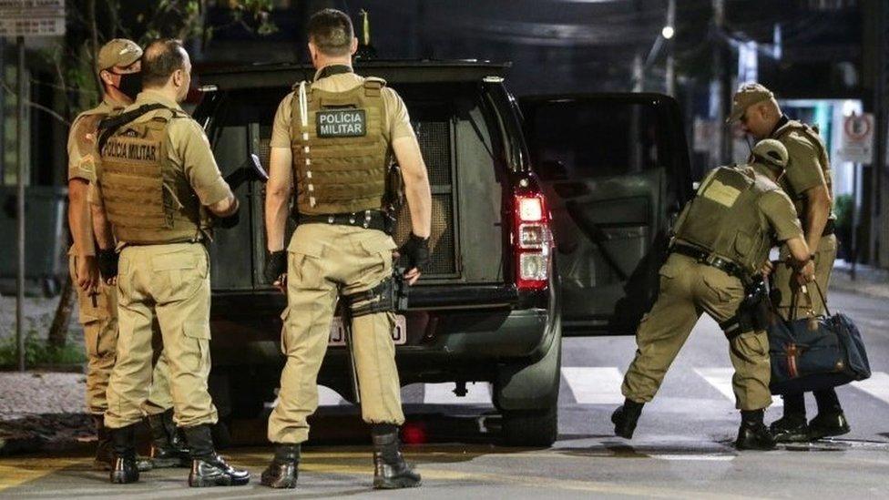 Police collect money left behind by assailants in the aftermath of a bank robbery in Criciuma, Brazil, 01 December 2020.