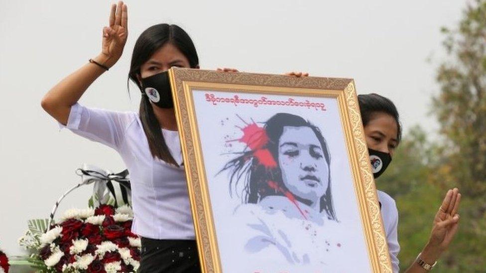 Myanmar women hold up a portrait of slain protester Mya Thwe Thwe Khaing