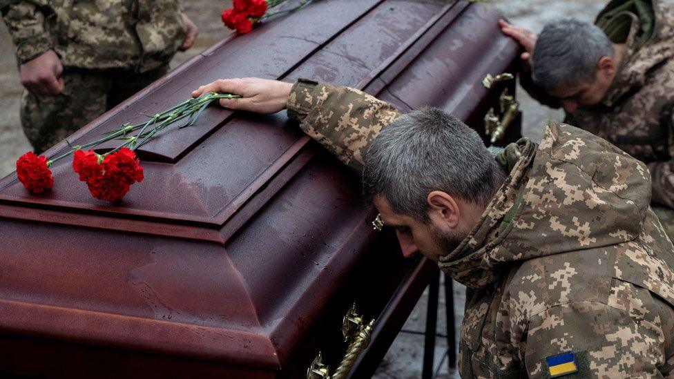 Ukrainian army members mourn next to the coffin of Pavlo Vedybida, a Ukrainian serviceman and ultras member of Football Club Obolon Kyiv, who was killed in the battle near the town of Chasiv Yar, Donetsk region, during the funeral ceremony at a cemetery in Kyiv on 30 November 2024