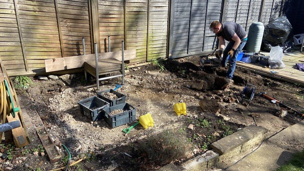 Man working on garden, surrounding by bare earth