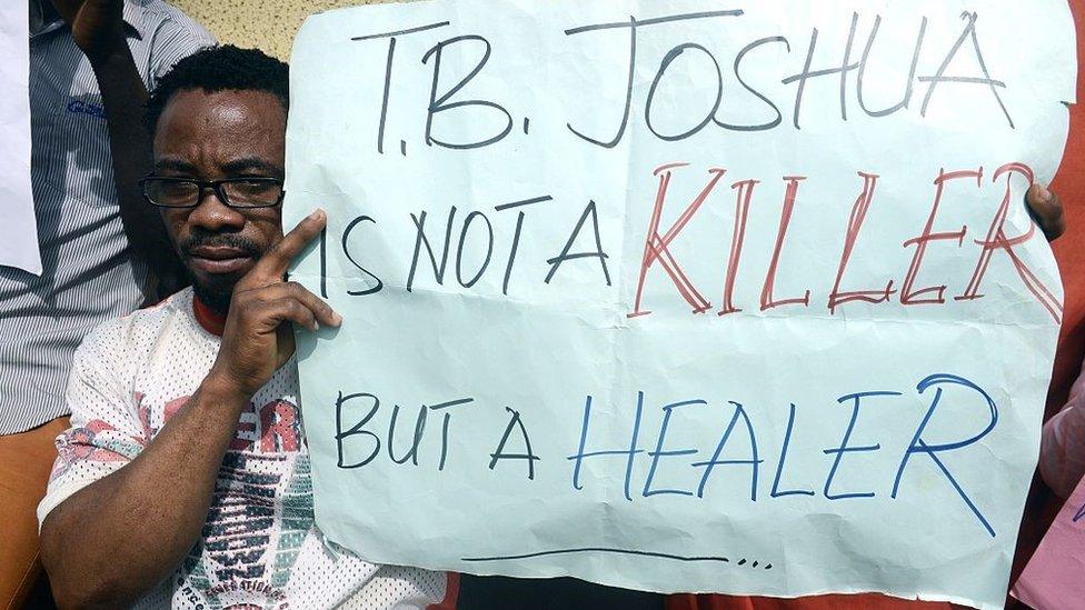 A disabled man holds a placard to protest the coroner's inquest on October 30, 2014 during the hearing at the Ikeja High Court in Lagos into the cause of the September 12 collapse at a guesthouse of the Synagogue Church of All Nations