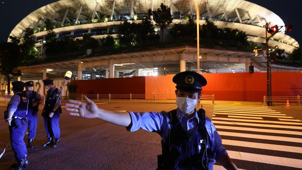 police man with mask next to Olympic stadium in Tokyo.