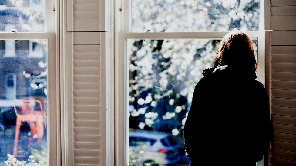 women looks out of window with back to camera