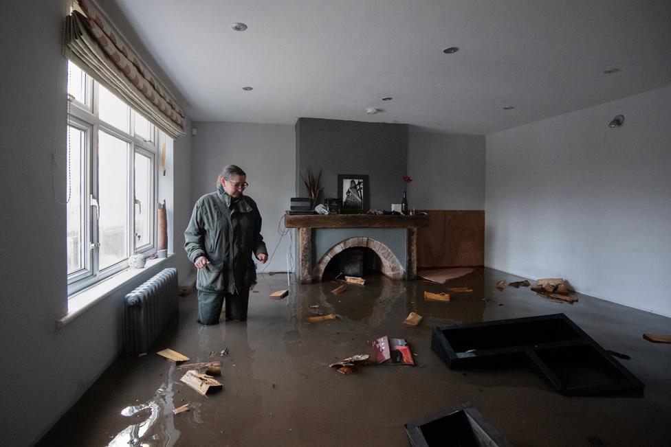 A woman stands in her flooded home on the outskirts of Lymm in Cheshire, 21 January 2021