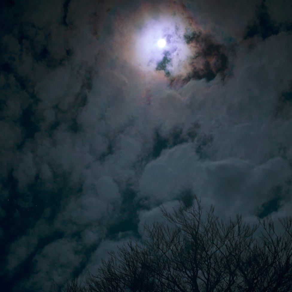 An image of the moon shining through clouds