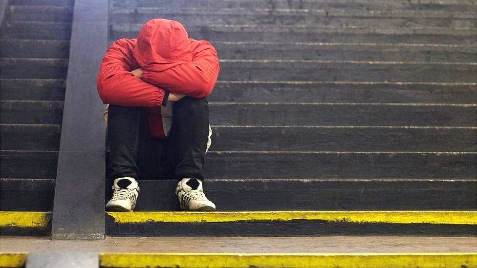 Young homeless man sitting on steps.