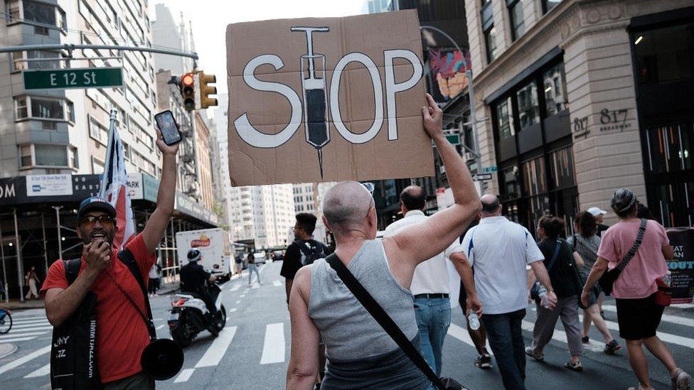 woman at protest holding stop vaccines sign