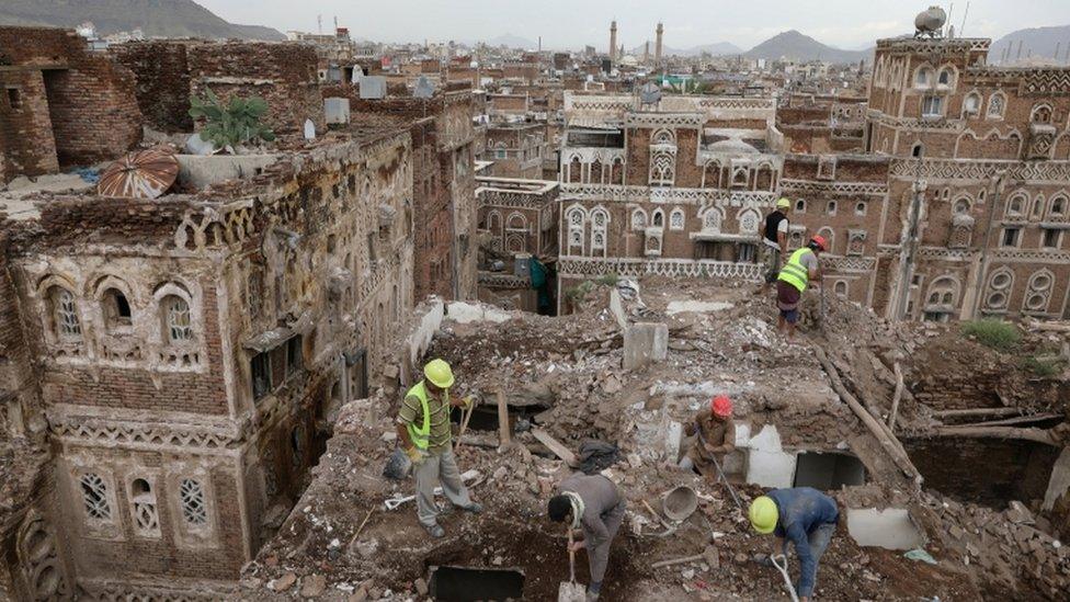 Worker on a roof of a damaged building in the Yemeni capital Sanaa