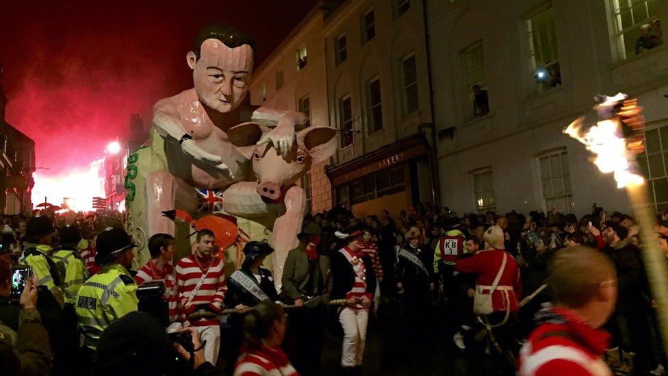 A crowd takes photos of the David Cameron effigy as it is paraded through Lewes