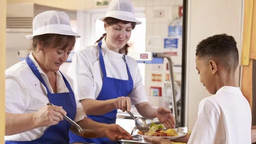 Stock picture of a child being dished out lunch at school