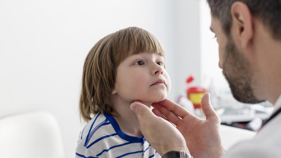 Child having tonsils checked by doctor.