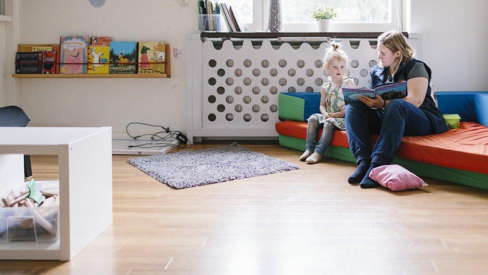 A nursery worker reading with a child