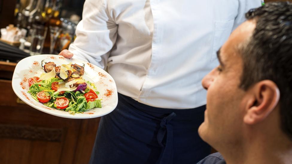 Waiter showing food to diner (stock shot)