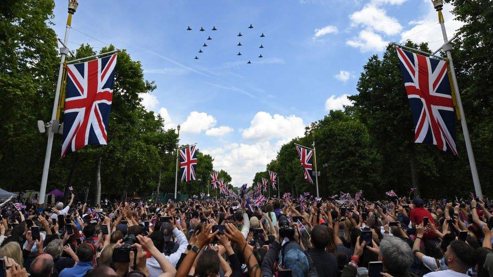 Flag-waving spectators look up as a group of planes fly in formation to spell out '70' to mark the Queen's reign