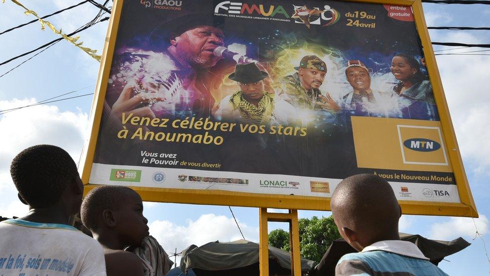 Children look at a poster announcing the Femua music festival