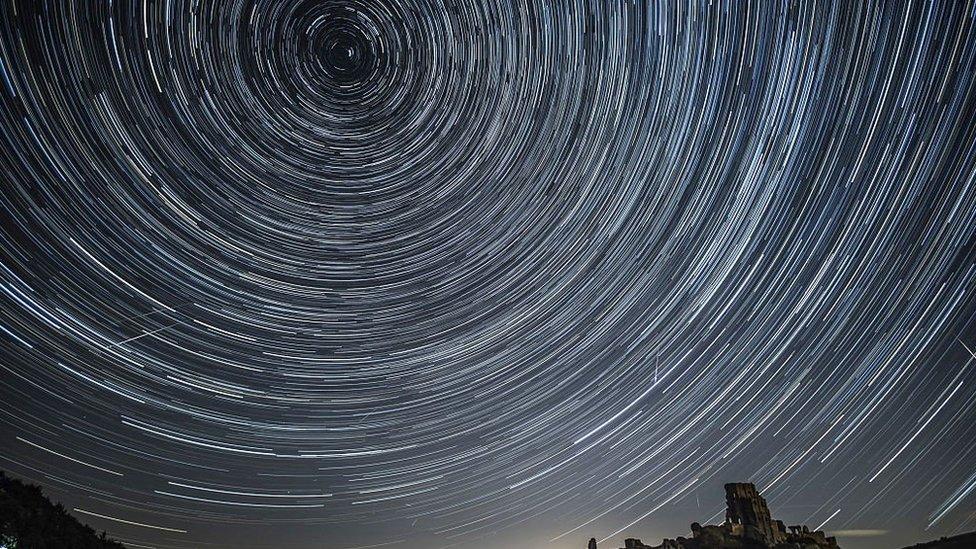 A long exposure shot of a meteor shower has produced streaks of white lines in a circle in the night sky