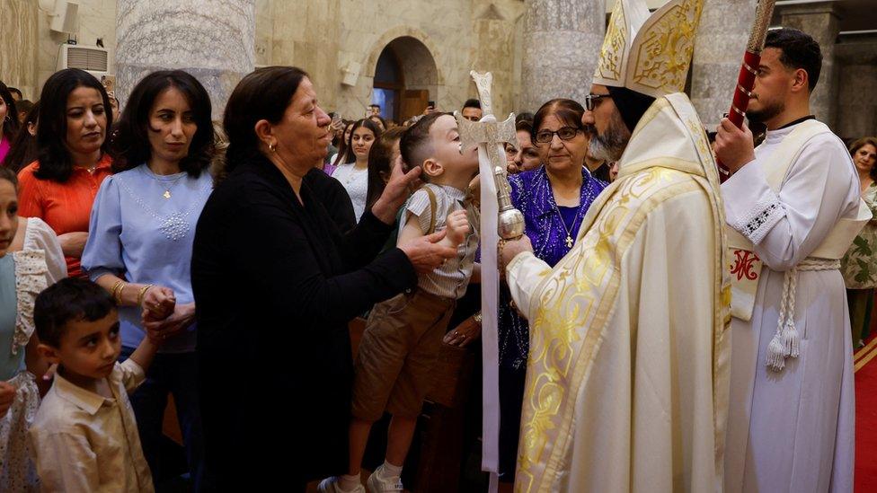 A worshipper kisses a cross during an Easter vigil service at the Grand Immaculate Church in Al-Hamdaniya, Iraq