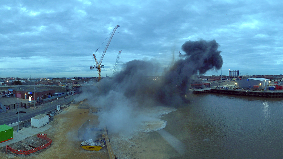 Smoke billowing up into the sky when a bomb exploded in Great Yarmouth. Yellow cranes can be seen in the background and an industrial estate on the other side of the river