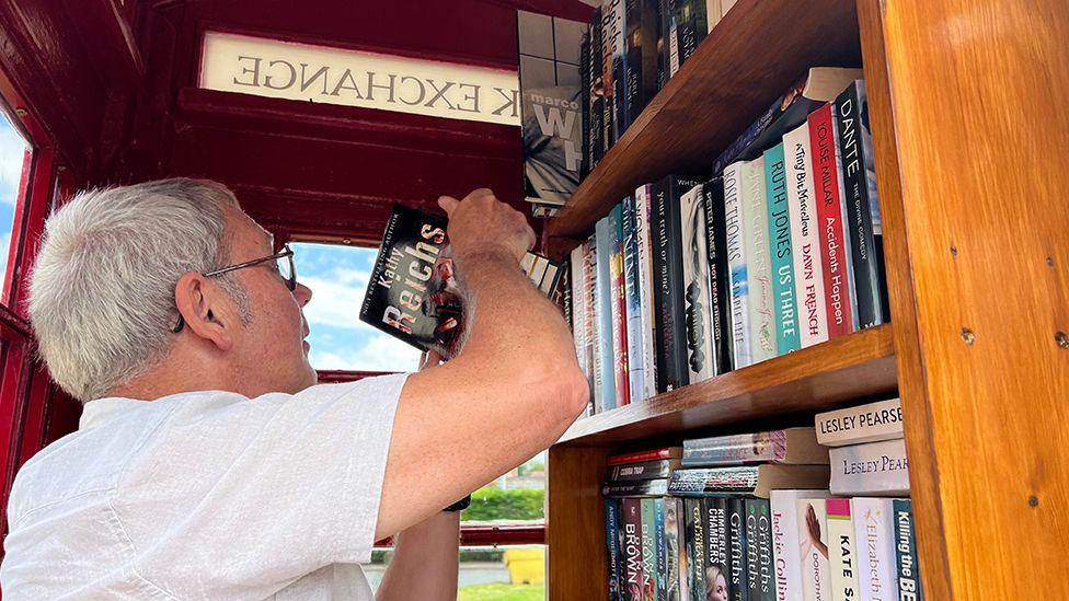 Inside view of the phone box showing books on shelves 