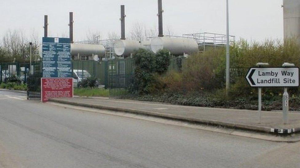 The road leading to the former Lamby Way landfill site in Cardiff, with a sign pointing the way, and industrial equipment in the background