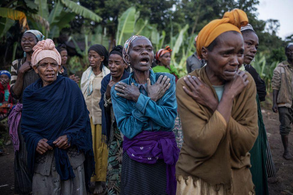 Women weep while residents and volunteers leave for the night after digging in the mud in search for survivors and bodies at the scene of a landslide in Gofa, Ethiopia on July 24, 2024.