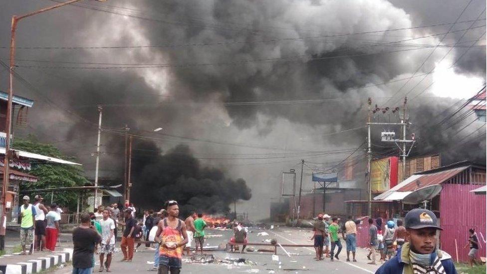 Large clouds of smoke are see amid debris and fire on the streets of Manokwari, Papua