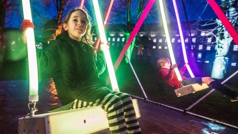 Two children on a light-up swing installation