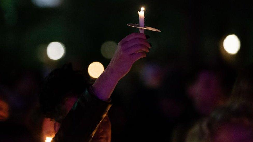 A person holds up a candle at Sackville Gardens in Manchester