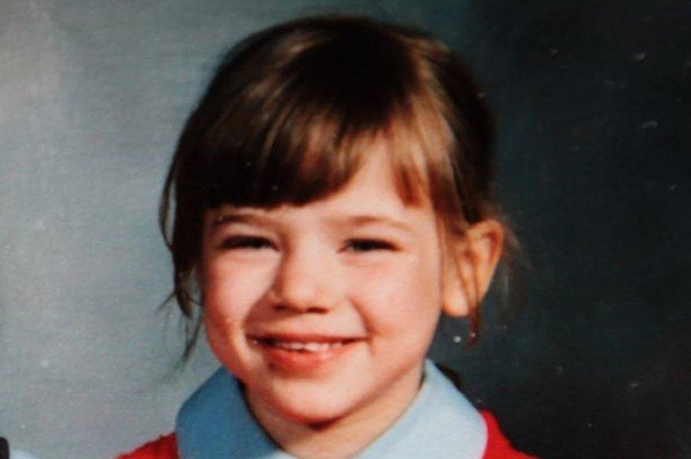 Nikki smiling in a red jumper