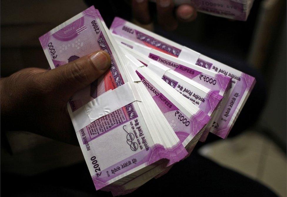 A cashier displays the new 2000 Indian rupee banknotes inside a bank in Jammu, November 15, 2016.