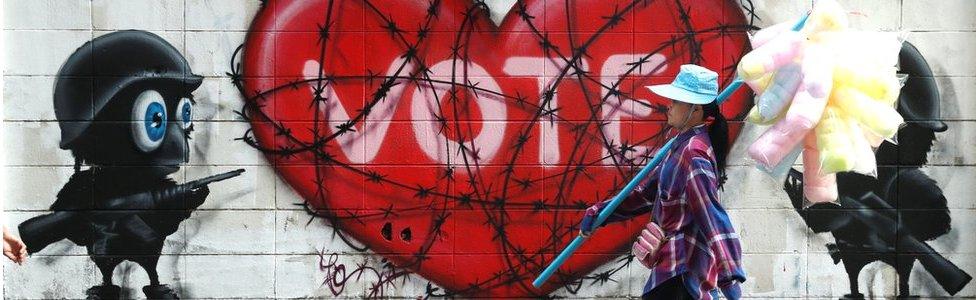 Woman walking past a "Vote" graffiti