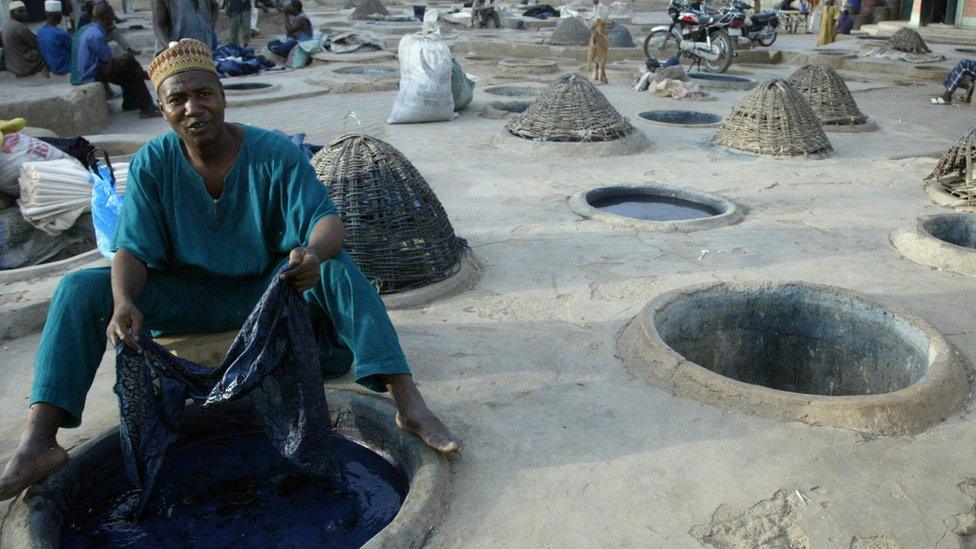 Man sat with fabric at Kano dye pit.