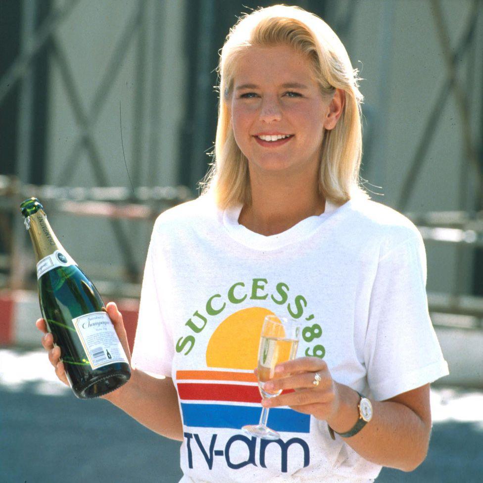 Ulrika in a T-shirt with the words "Success '89" and the TV-am logo, holding a glass of champagne in one hand and a bottle in the other