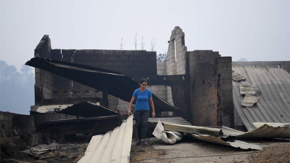 A woman checks the damage in Vila Nova near Vouzela as wildfires continue to rage in Portugal 16/10/2017