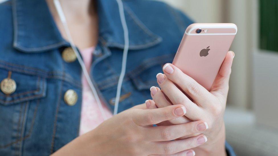 A woman holding a rose gold iPhone 6S