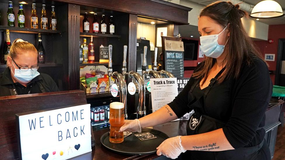 A bar worker puts drinks on a tray