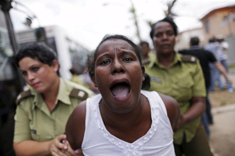 A member of the "Ladies in White" dissident group shouts as she is led away by police officers in Havana