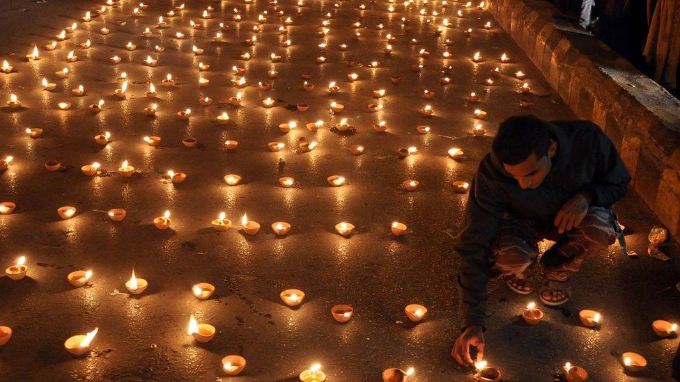 Pakistani people light candles to pray for the victims who were killed in an attack at the Army run school in Peshawar